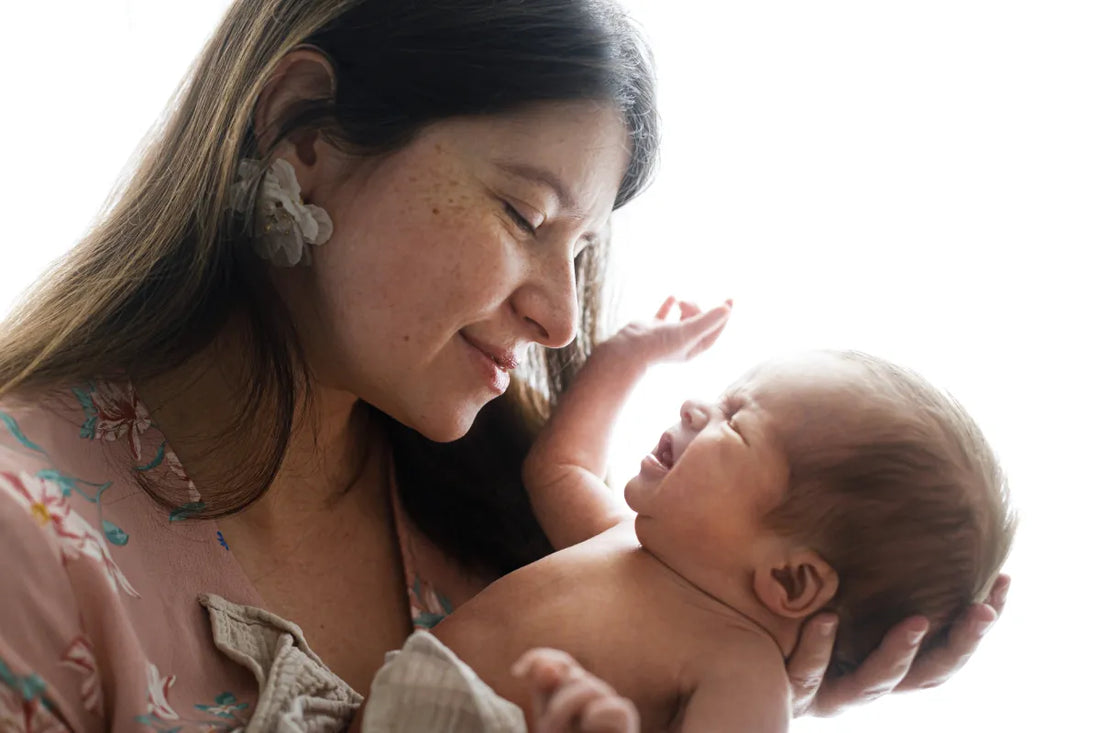 Smiling woman cupping her baby's face – hydrated skin after tallow balm use