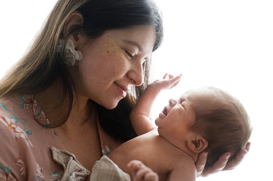 Smiling woman cupping her baby's face – hydrated skin after tallow balm use